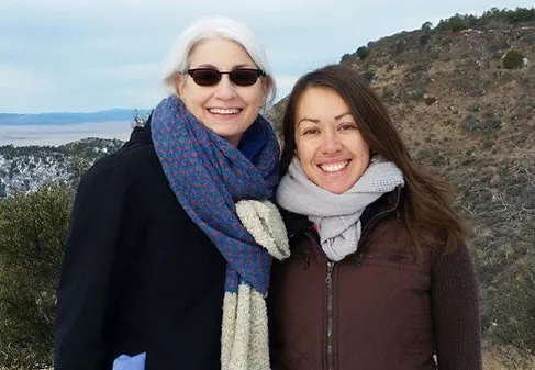 Two women on hiking trail smiling with scarves on.