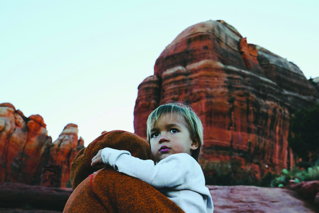 Little boy being held with mountain and cliffs in background