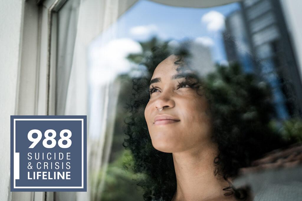 Woman Looking out window with 988 Suicide & Crisis logo in corner