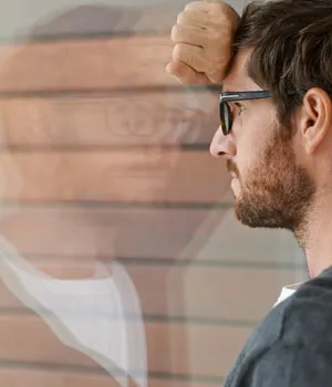 Man looking out window and his reflection.