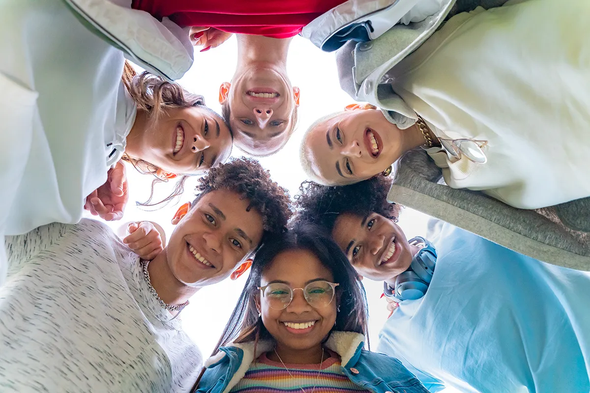 low angle of young people in circle looking at camera.