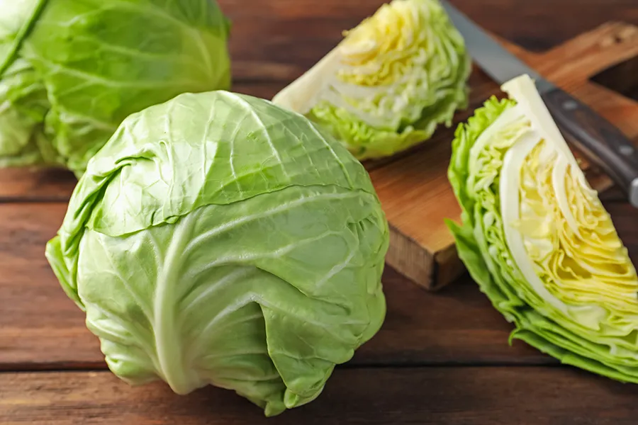 Green cabbage on wooden cutting board